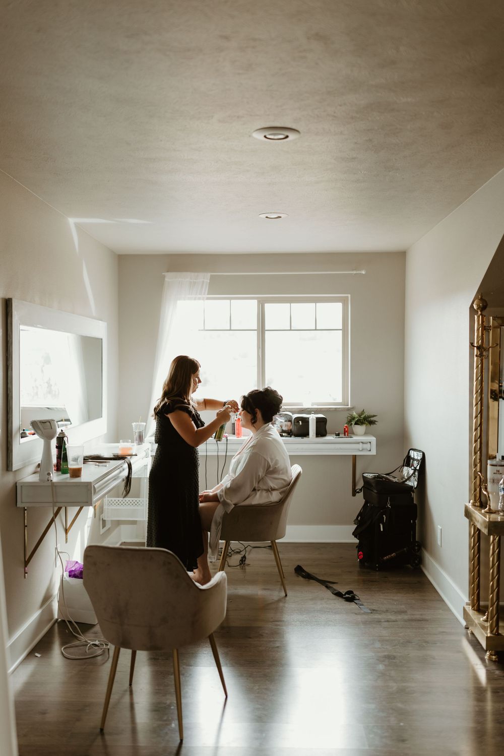 Hair styling session in a bright minimalist room with white walls and hardwood floors.