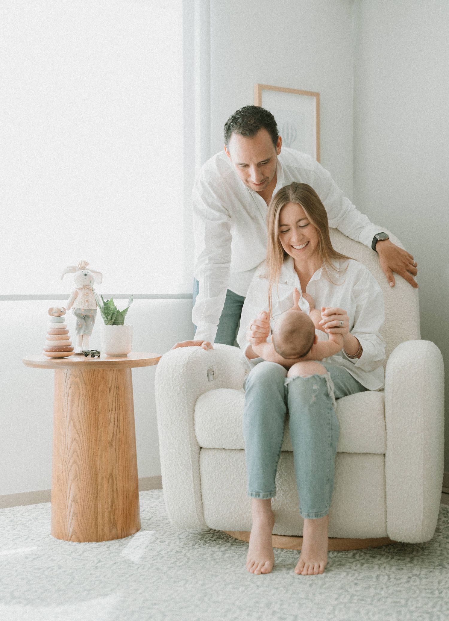 Family bonding moment in bright living room with white armchair and wooden side table.