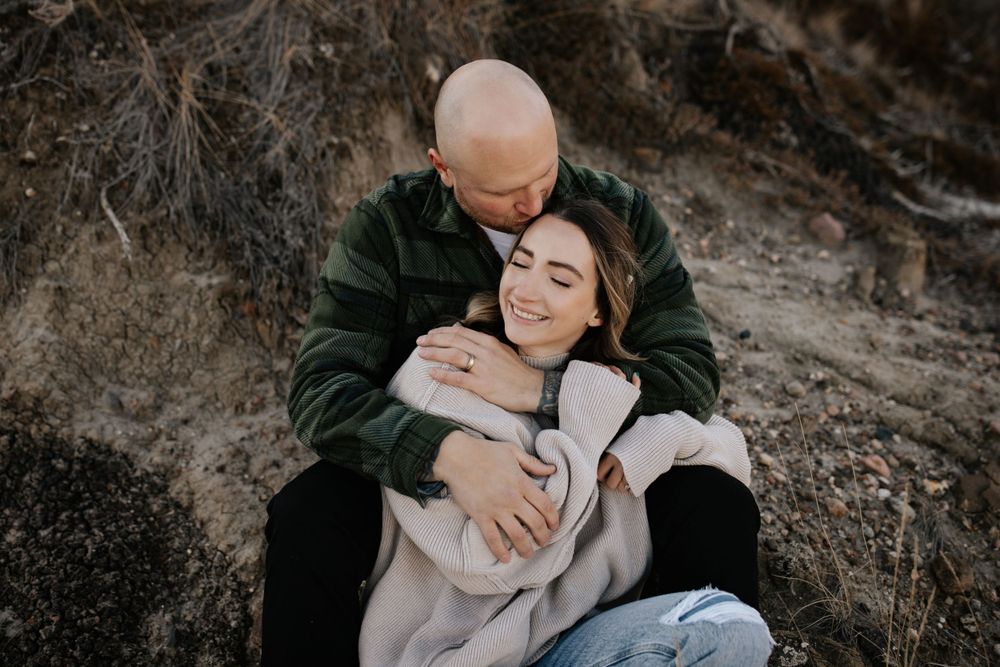 A couple shares an intimate moment against a rocky outdoor backdrop.