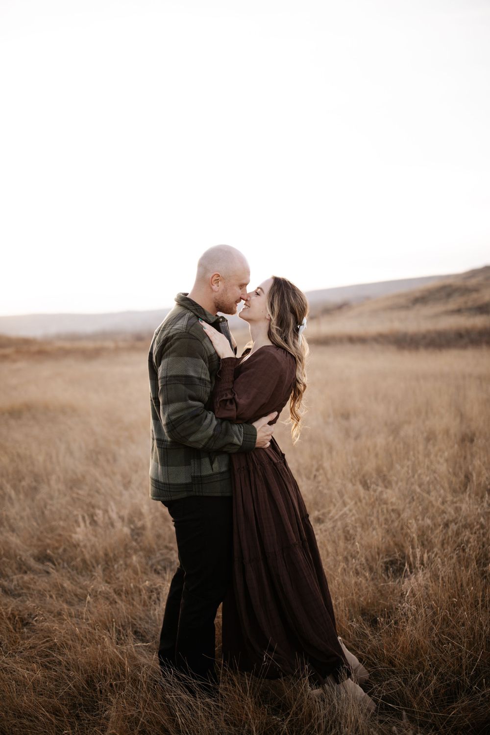 A romantic moment between a couple in a field at sunset.