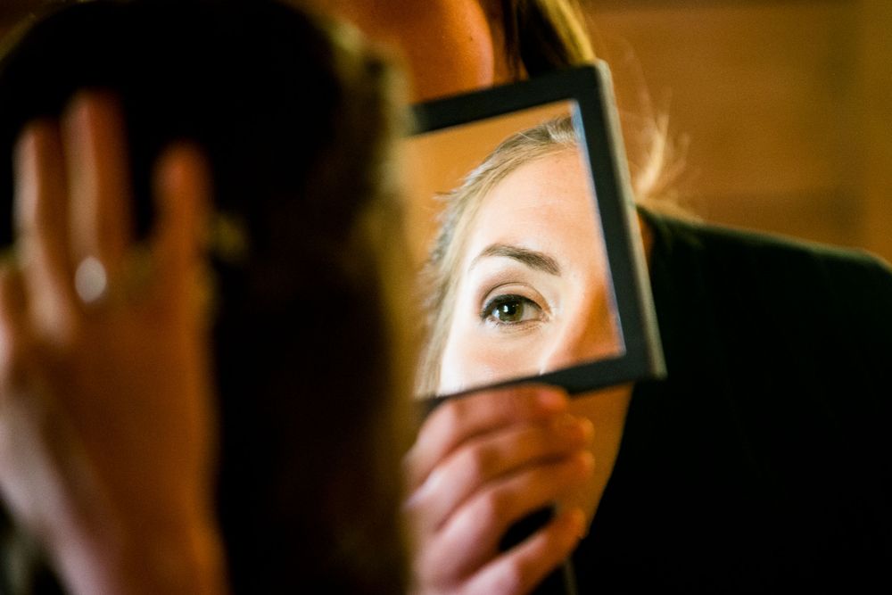 Close-up of a womans eye reflected in a small handheld mirror during wedding prep.