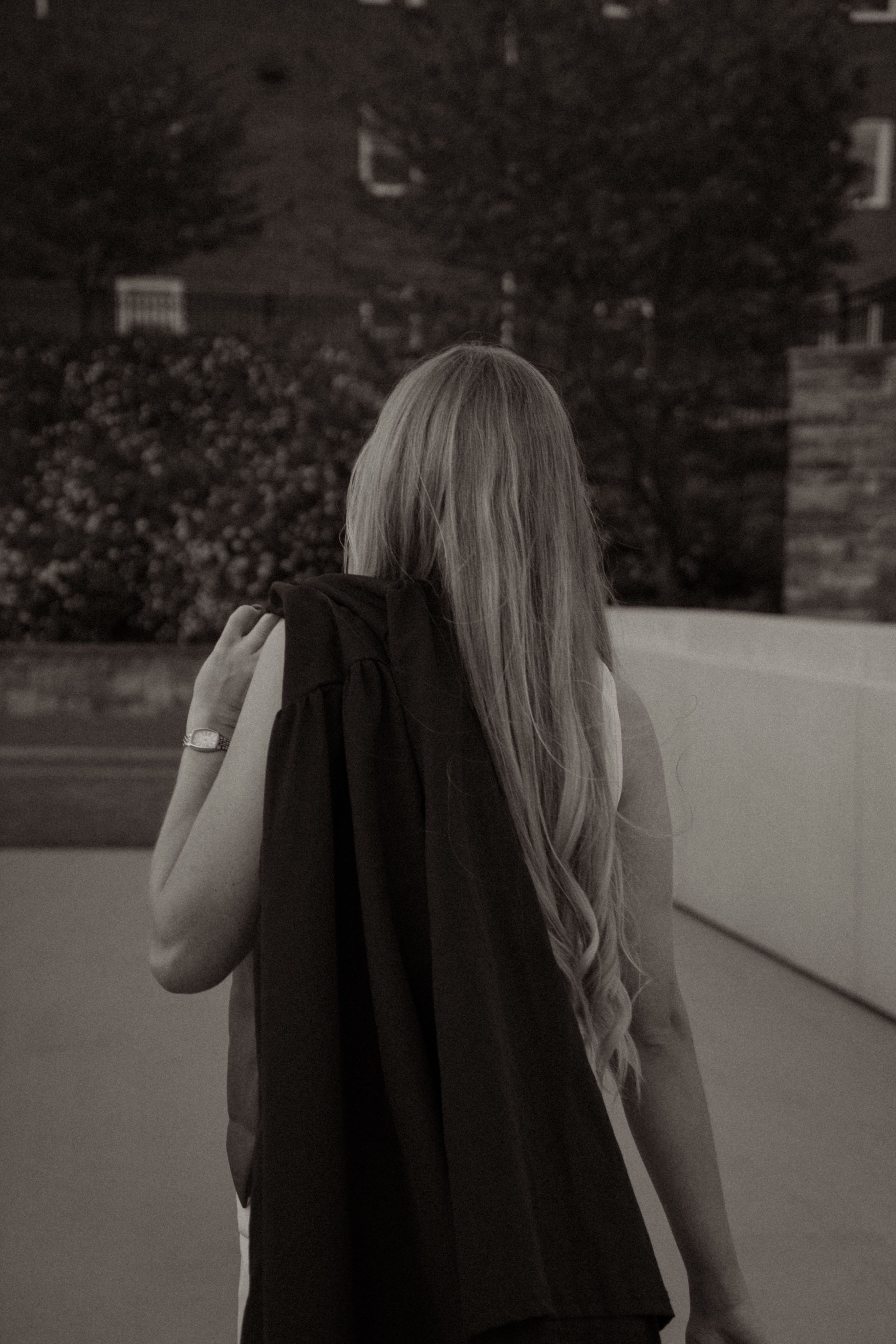 A black and white series of photos showing a person with long hair walking away from the camera.