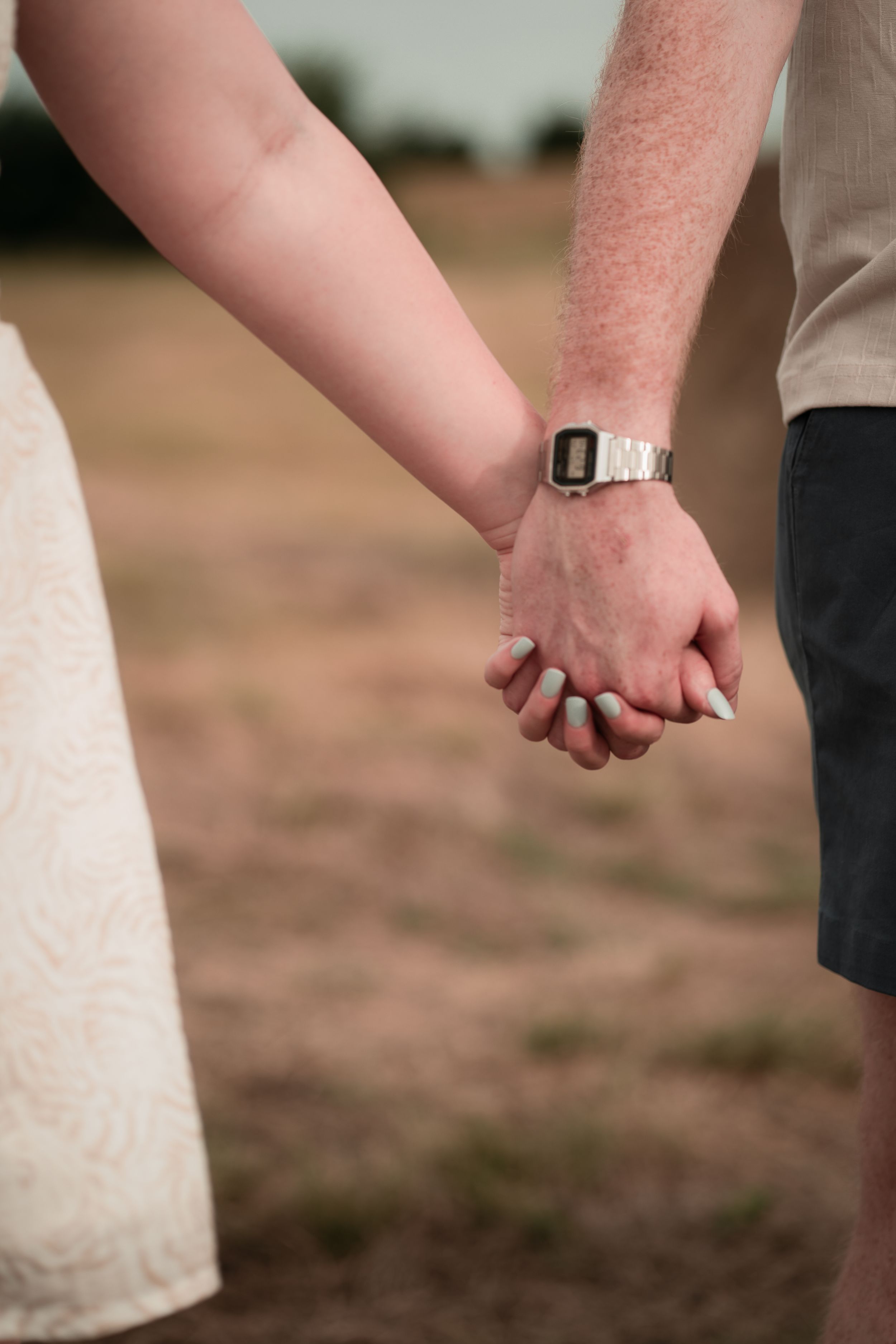 Close-up view of hands exchanging wedding rings during an outdoor ceremony.