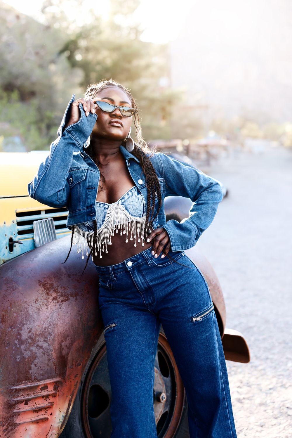 Retro fashion shoot with denim outfit against vintage car in golden sunlight.