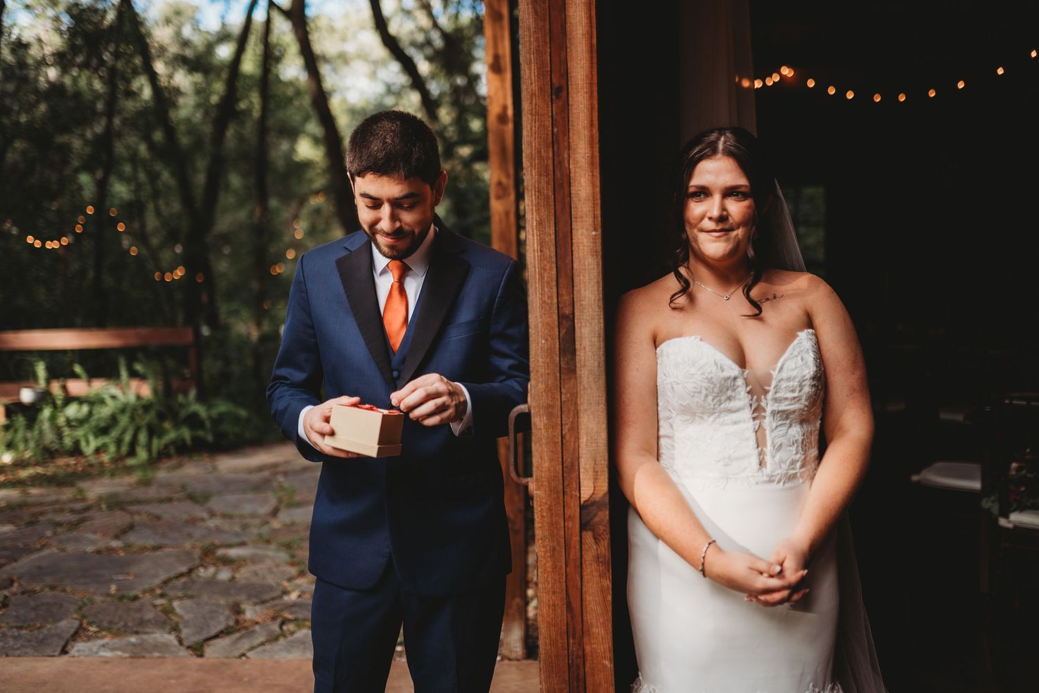 A wedding couple sharing a candid moment in front of a rustic venue entrance.