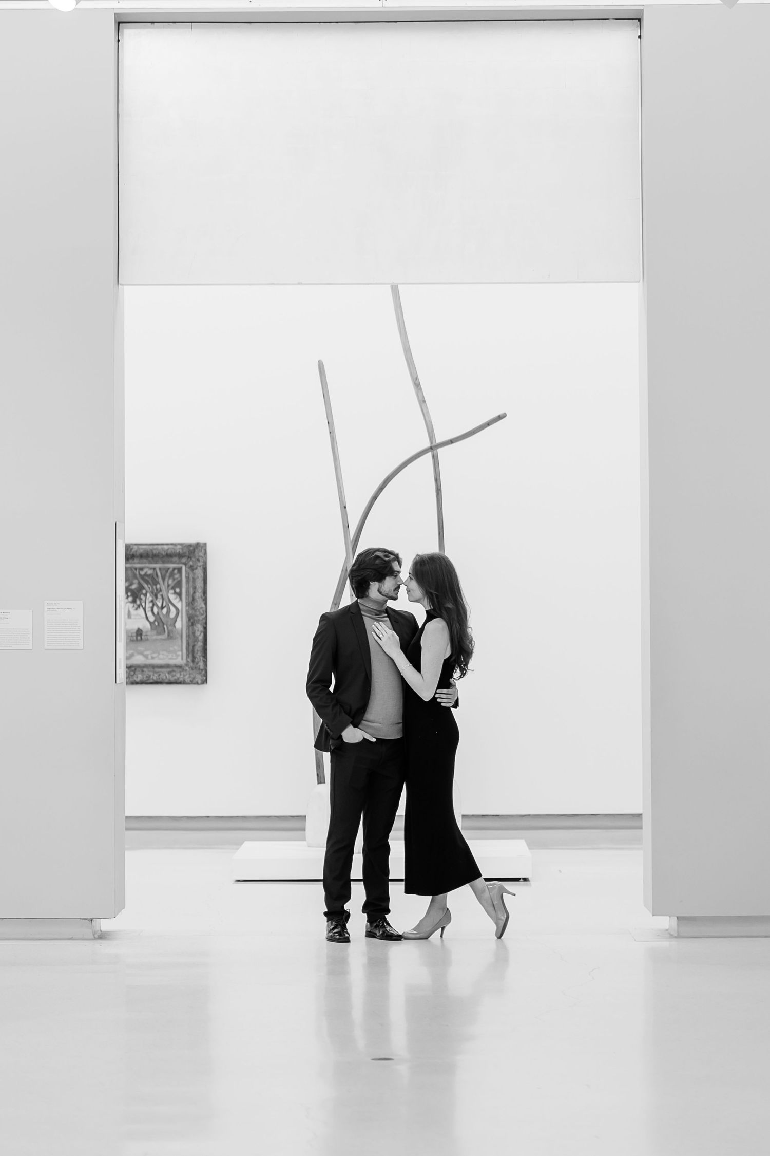 Minimalist black and white engagement photos in an art gallery.