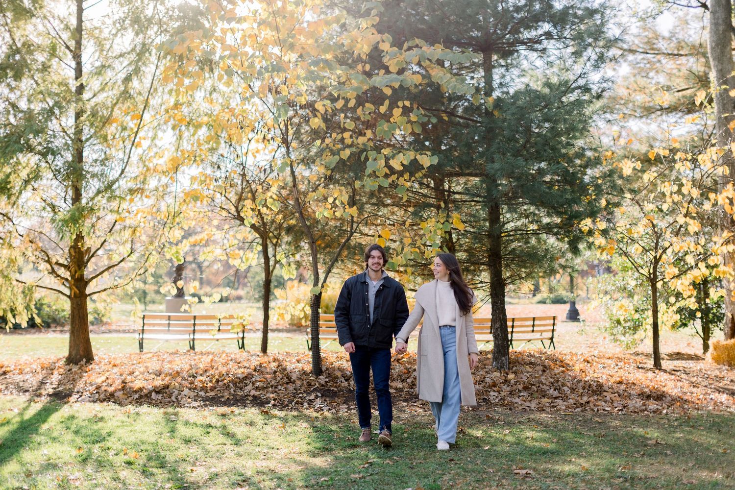 Couple walking through a tree-lined path during autumn.