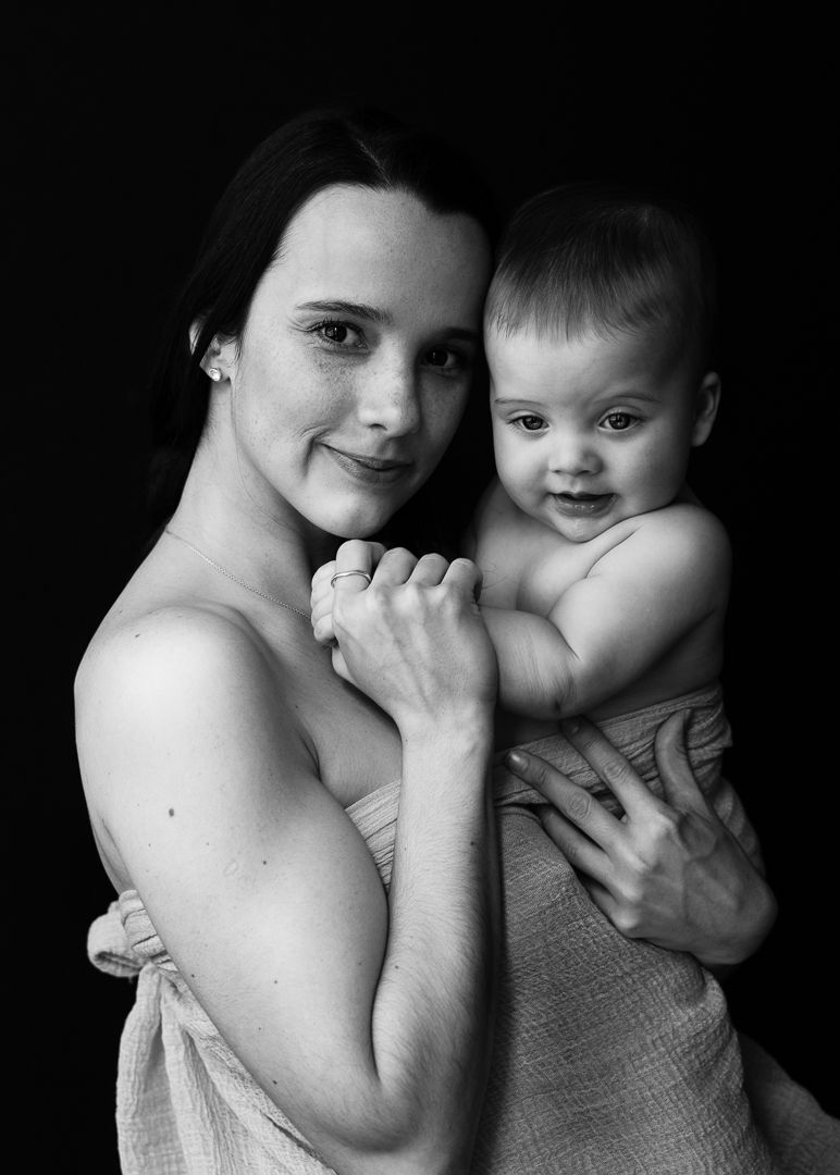 Tender black and white studio portrait of parent and smiling baby.