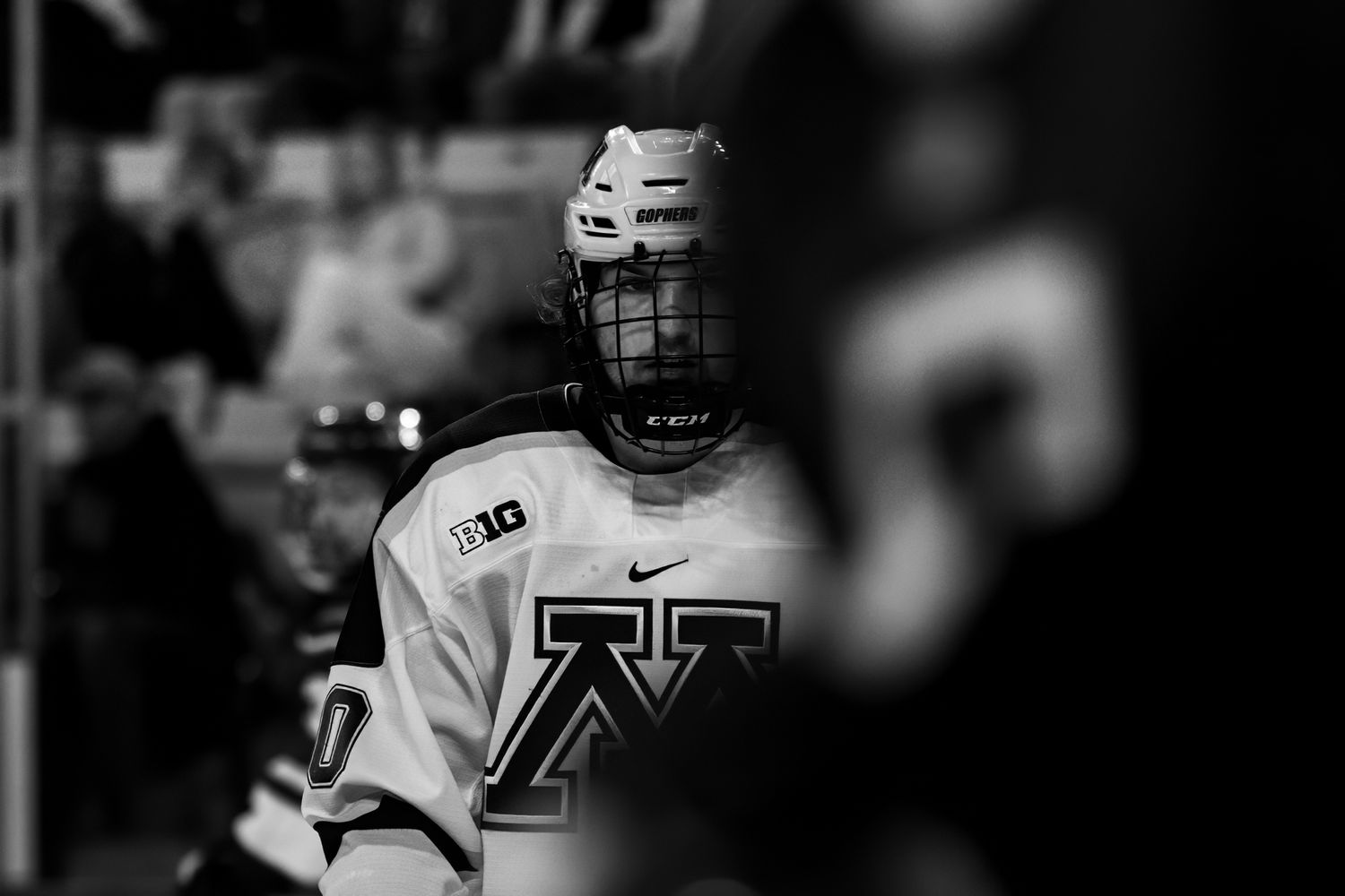 Hockey player in white university jersey captured in moody black and white.