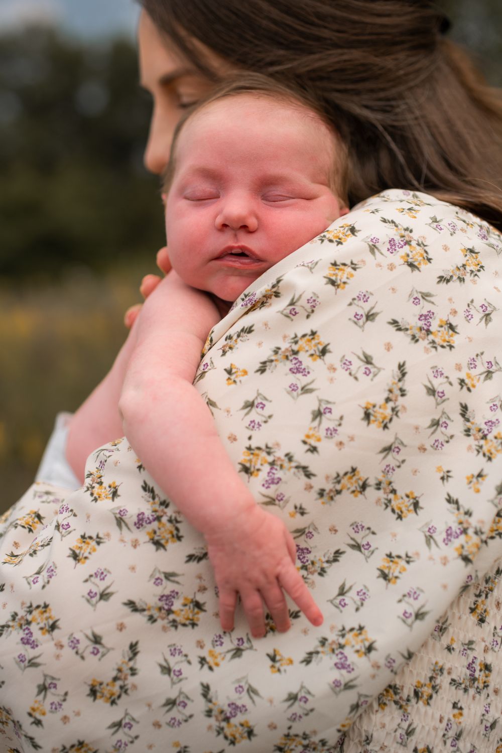 Sleeping infant resting peacefully against mother's shoulder.