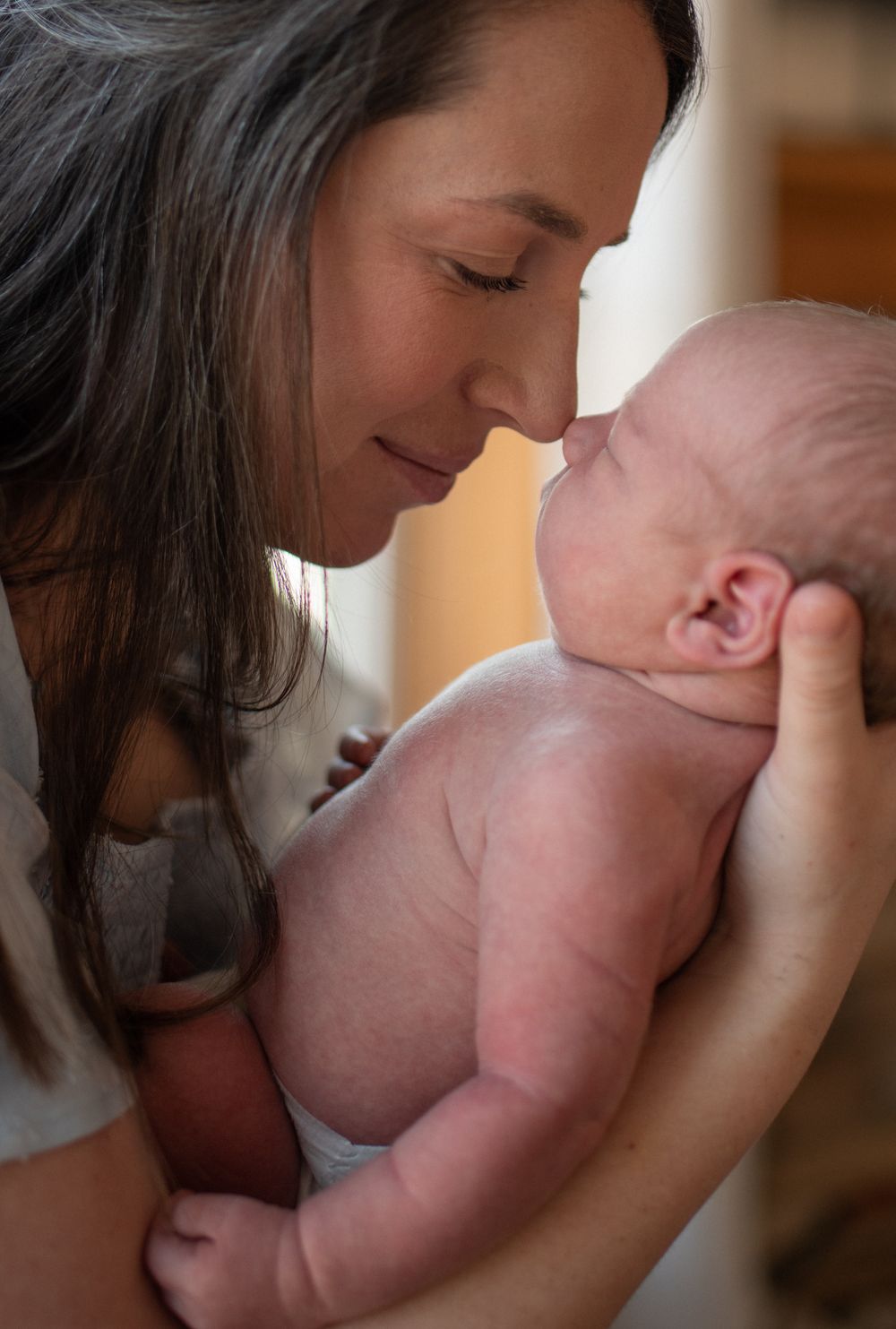 A tender moment between mother and baby showing nurturing affection and bonding in warm lighting.