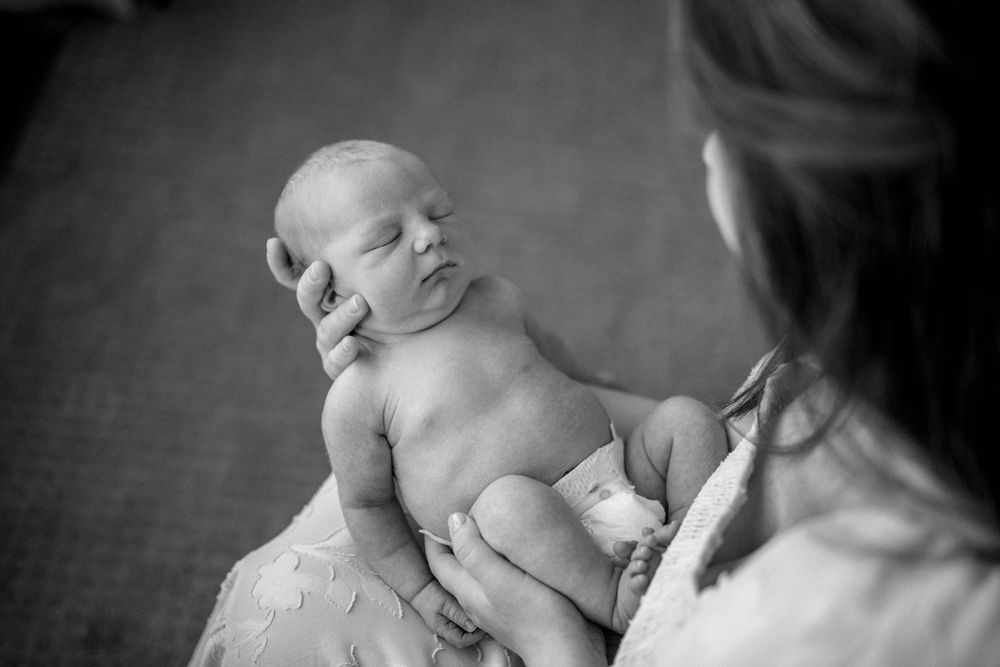 A tender black and white photo series showing intimate moments between a parent and newborn baby.