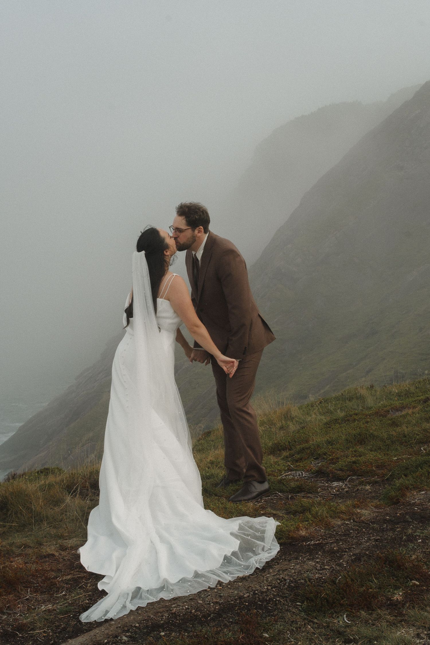 Bride and groom kissing behind yellow building in Glovertown
