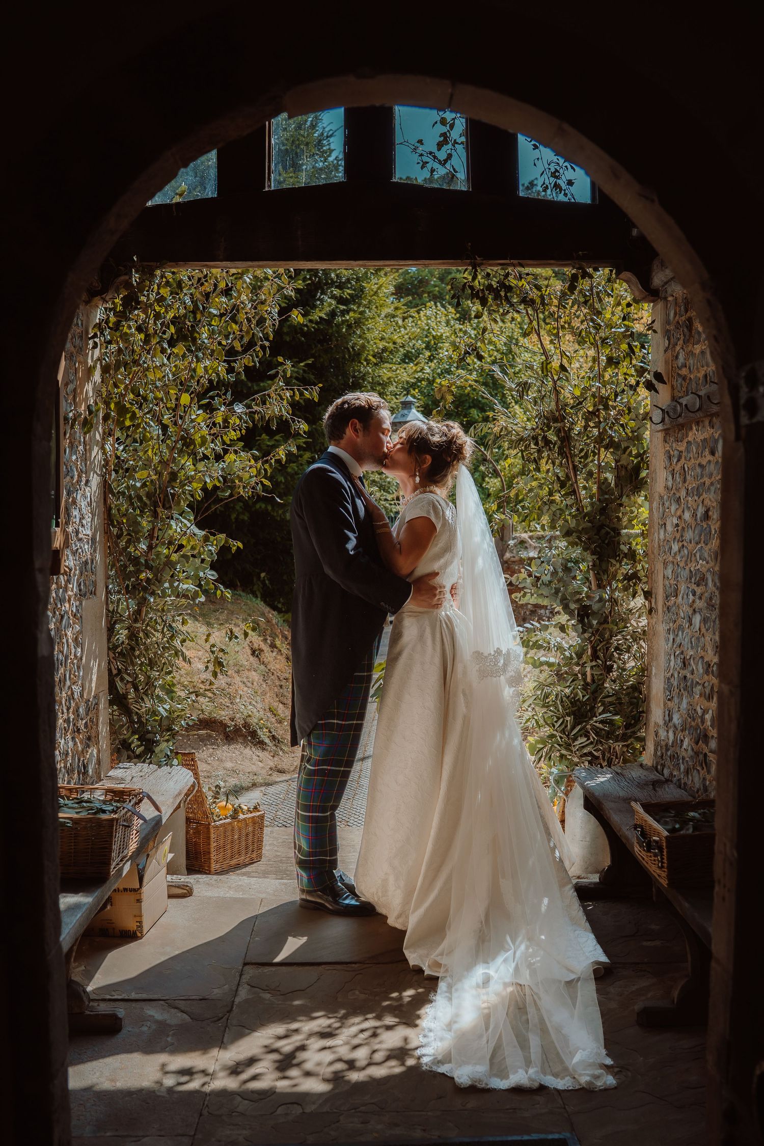 Romantic garden wedding portrait with couple embracing among blooming flowers.