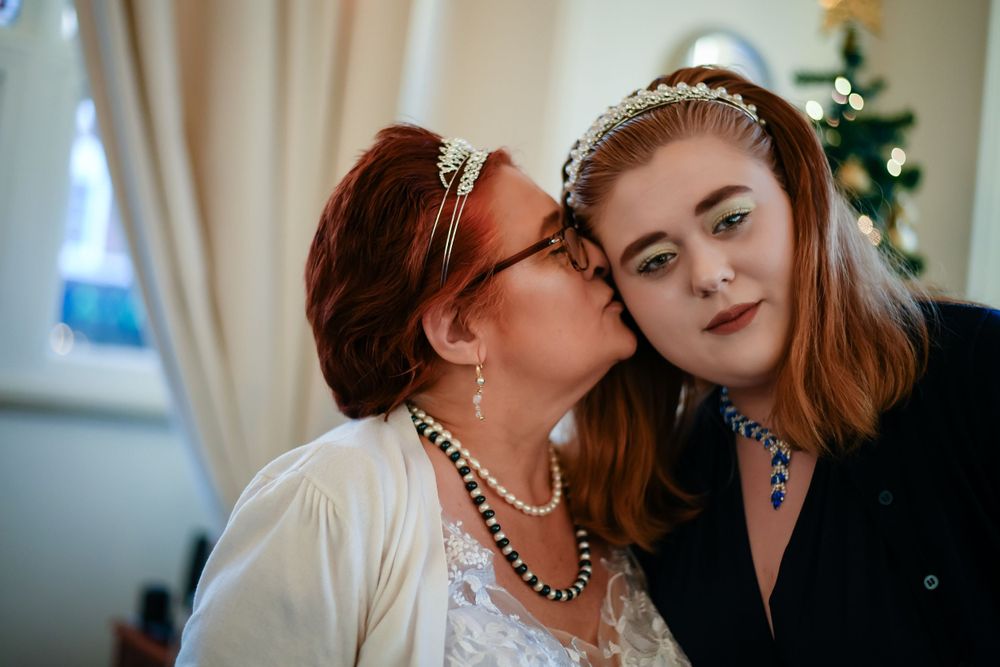 Candid moment between wedding participants with holiday decorations in background.