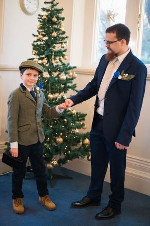 Holiday wedding scene with decorated Christmas tree and formal attire in elegant indoor setting.