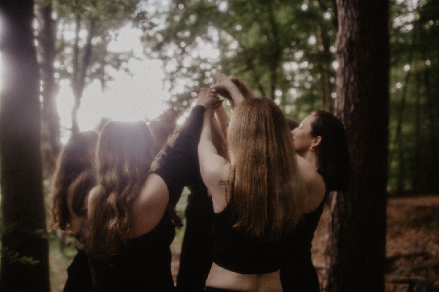 Eine Gruppe von Frauen in Kleidern tanzt bei Sonnenuntergang an einem See