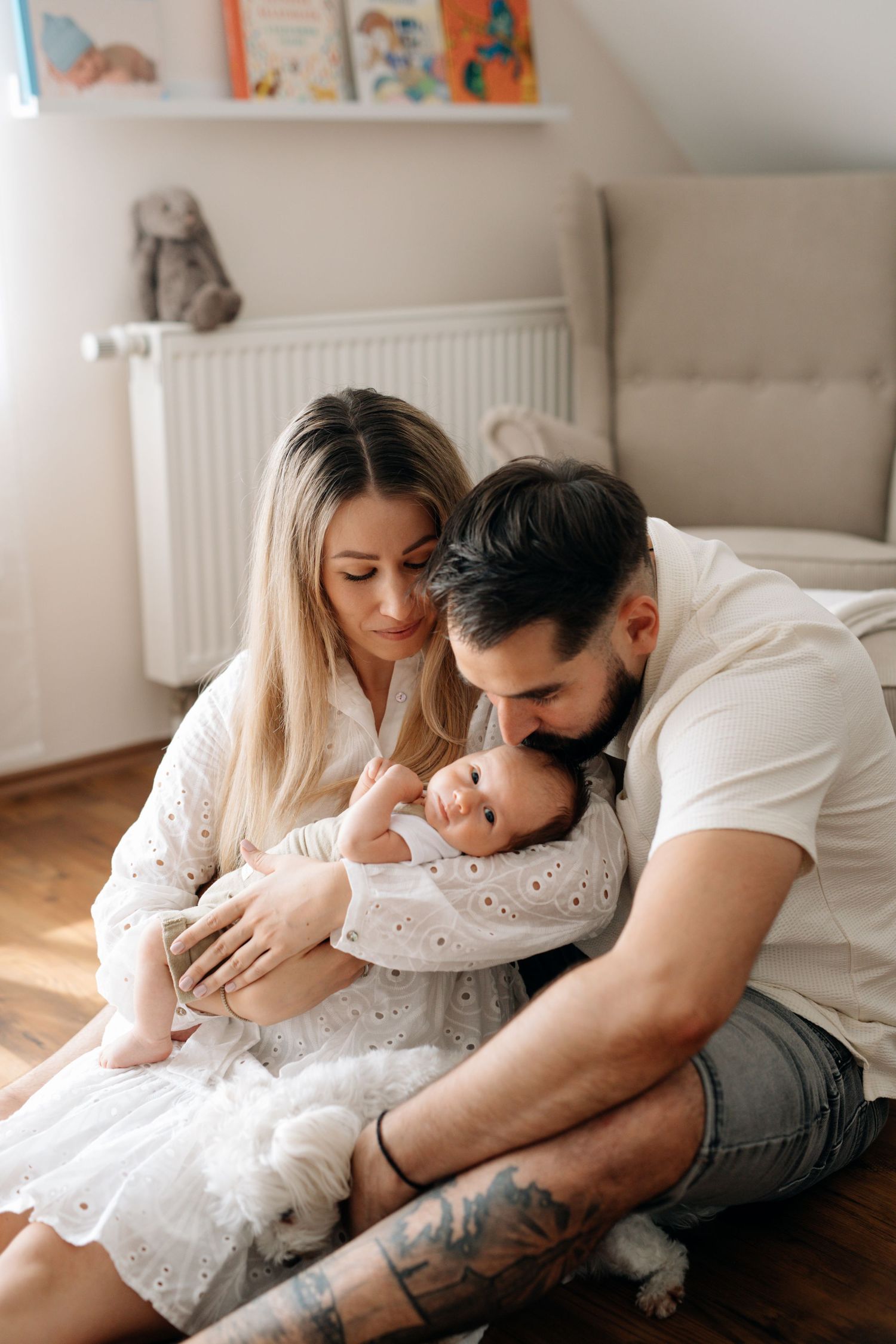 Tender family moment as parents cuddle with their infant on wooden floor.