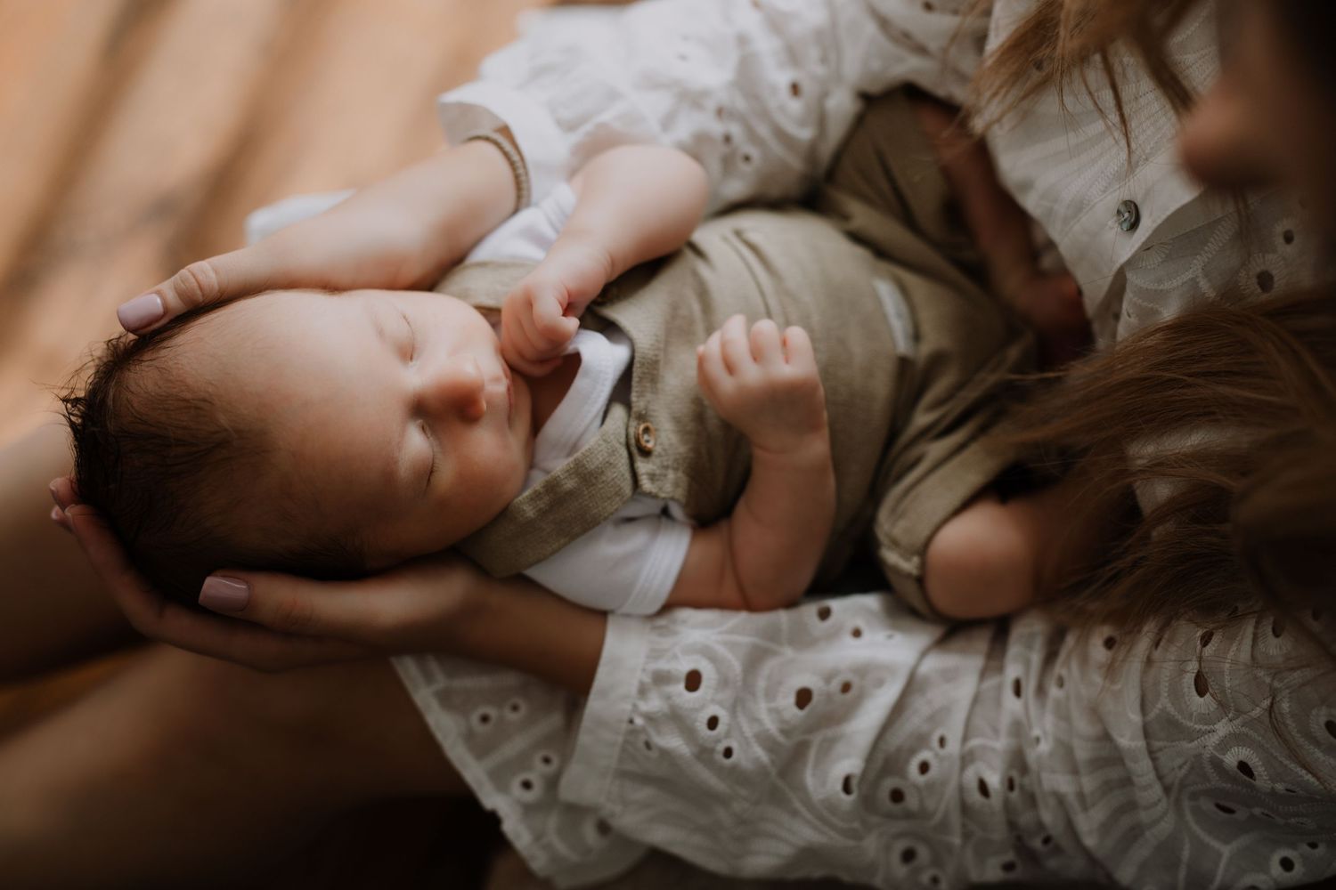A tender moment with a newborn baby resting on soft white eyelet fabric.