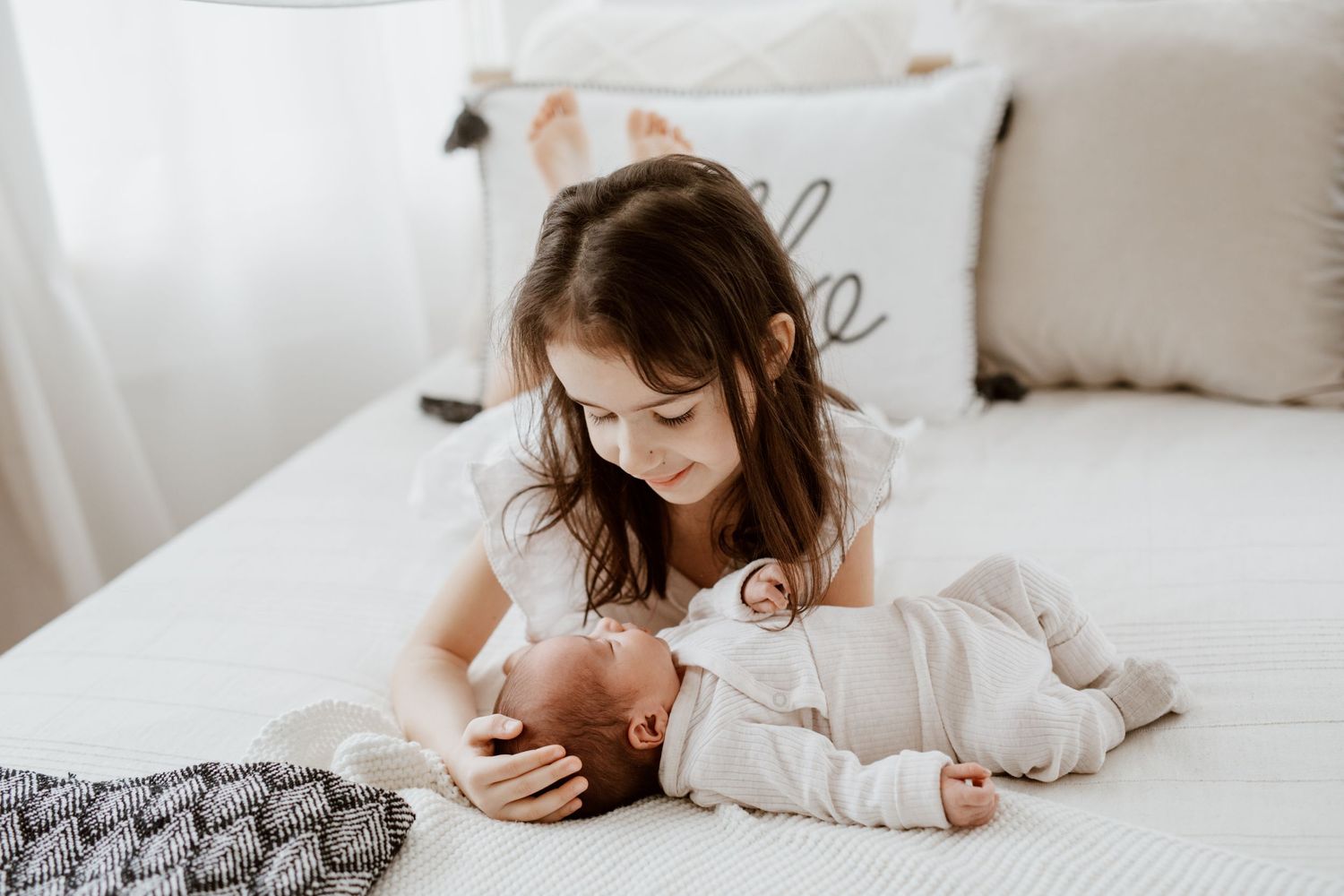 Sweet family moment with two siblings on a cozy white bed.