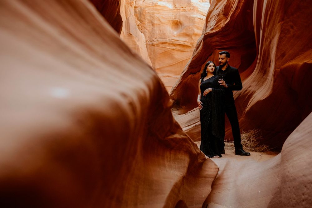 A person in dark clothing explores the smooth curves and narrow passages of Antelope Canyon in Arizona.