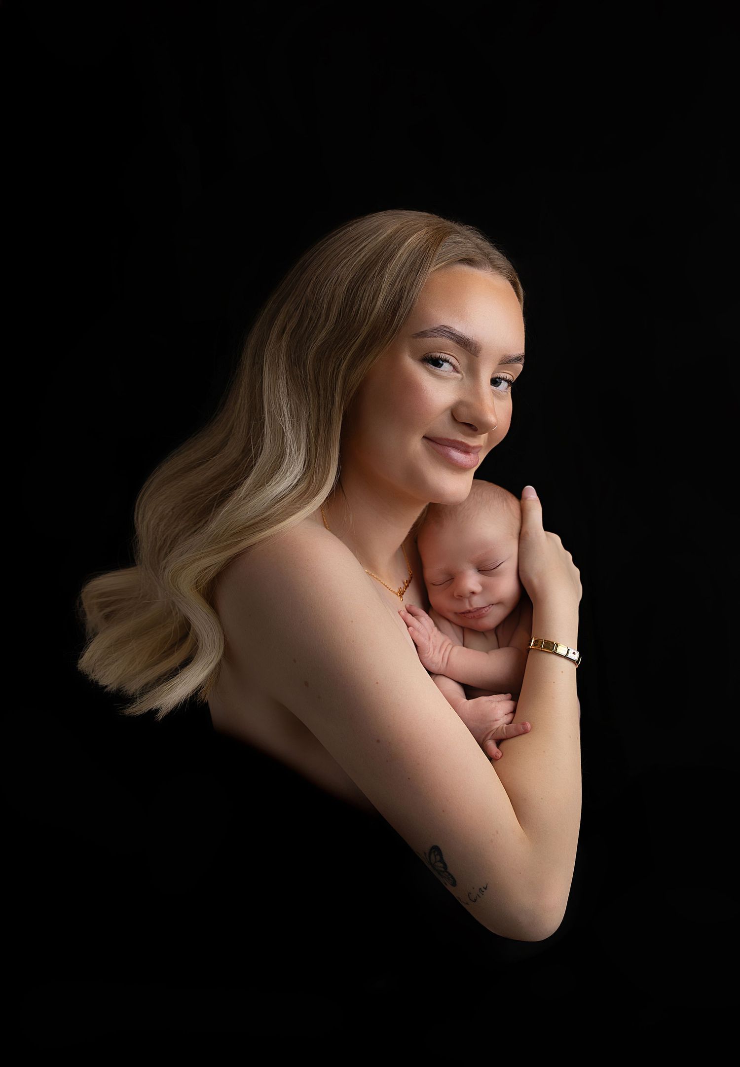 Image of mum holding her little boy wrapped in a black shawl smiling in coventry.
