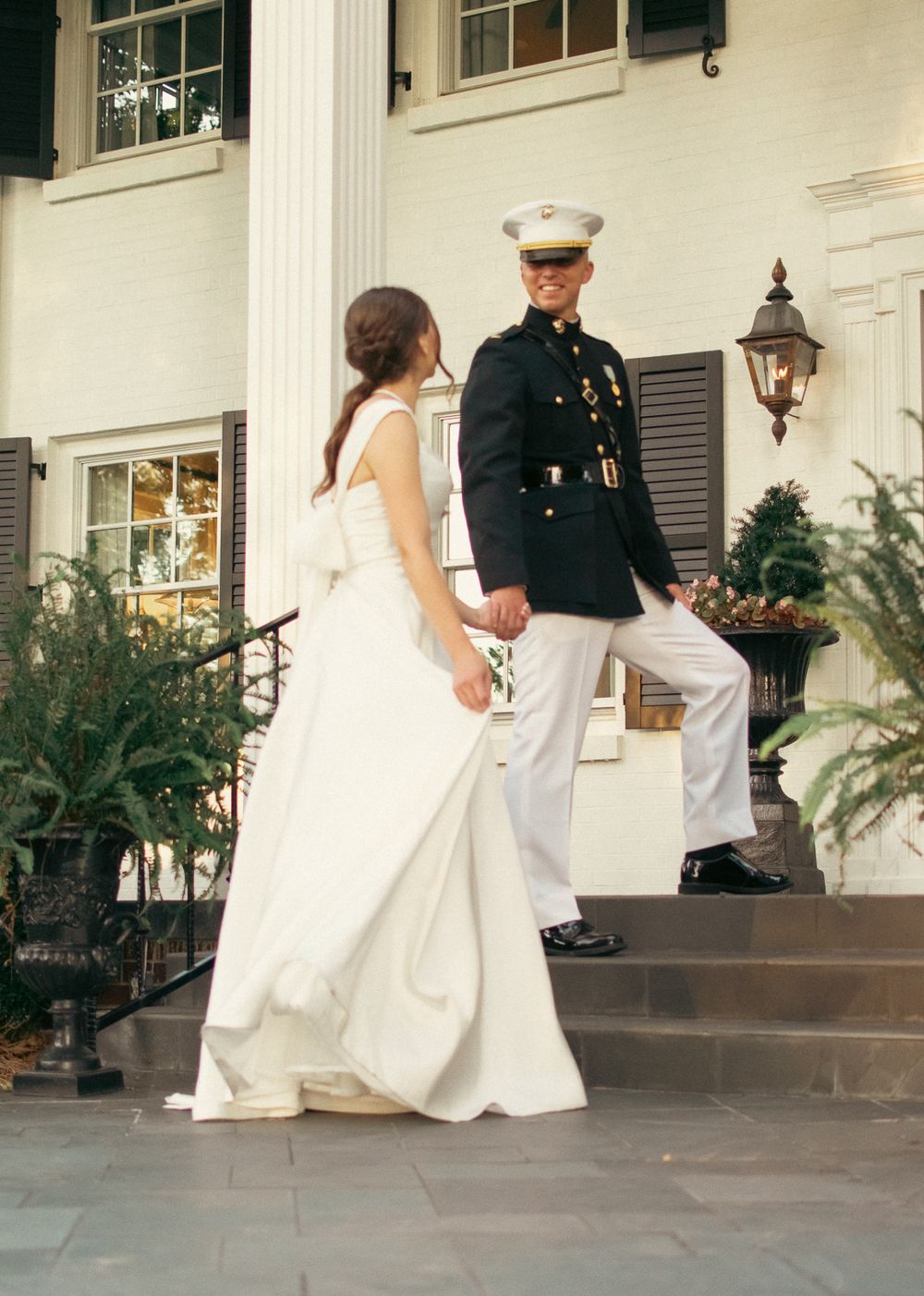 Elegant couple on stone steps with classic architecture and decorative lanterns.