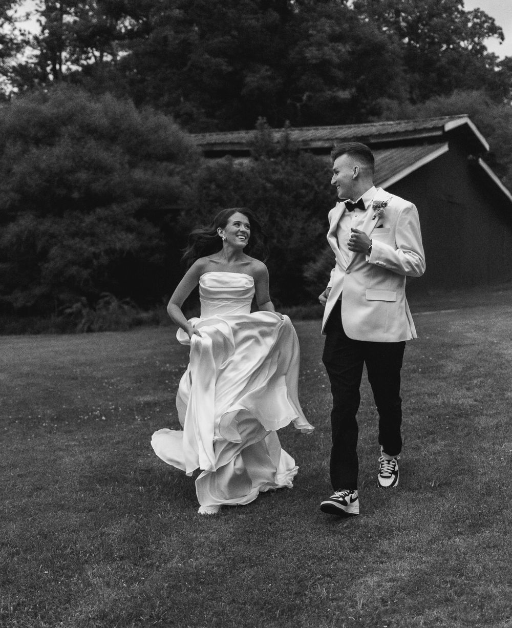 A playful wedding photoshoot on a grassy lawn with flowing white dress movement.