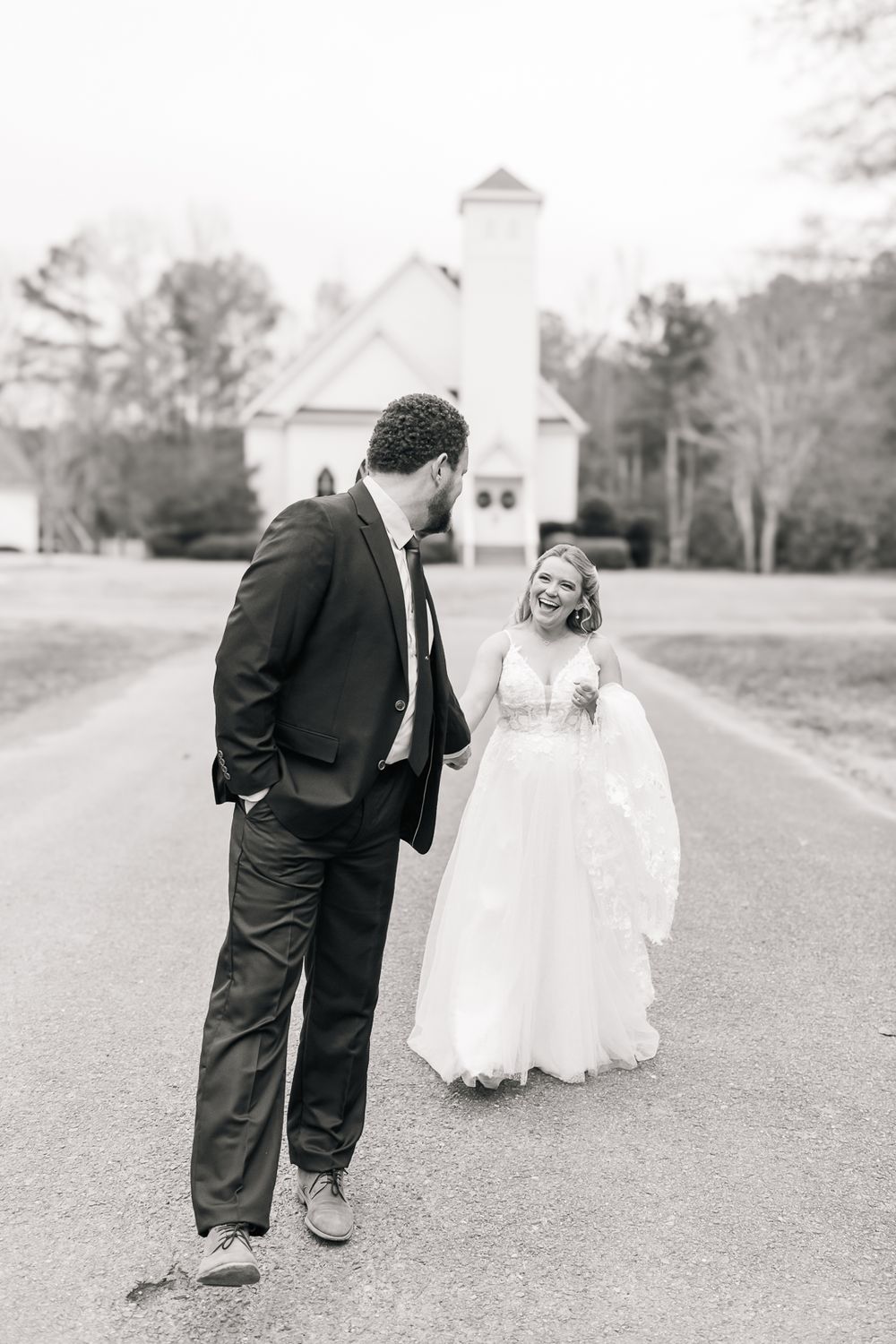 Sequential black and white photos of a couple's playful walk near a white church.