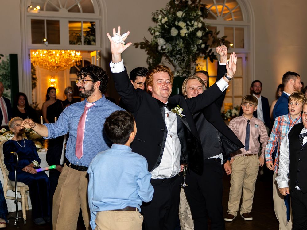 Wedding guests celebrate enthusiastically on the dance floor during reception festivities.