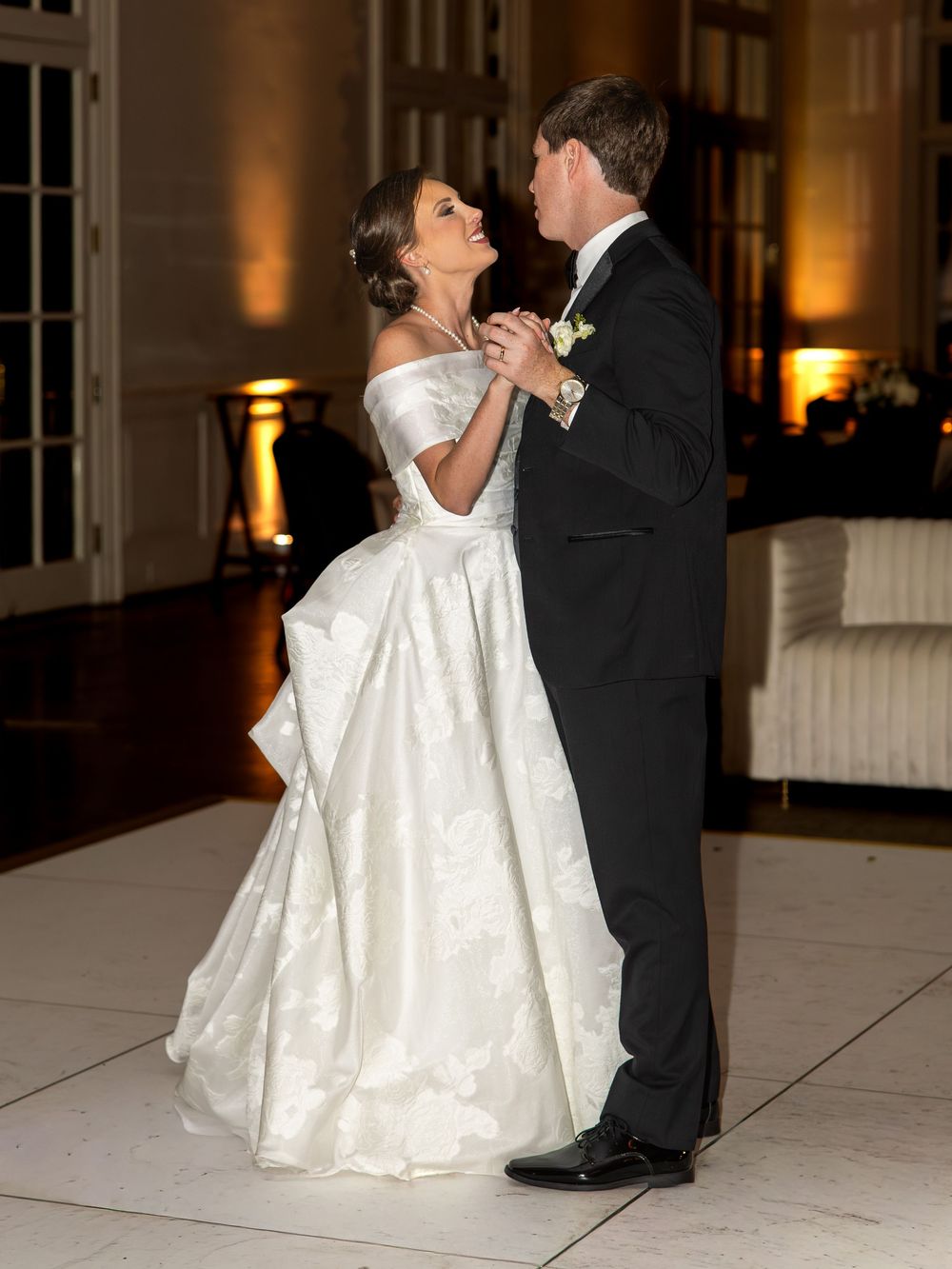 A couple shares an intimate dance moment on a white dance floor at their wedding reception.
