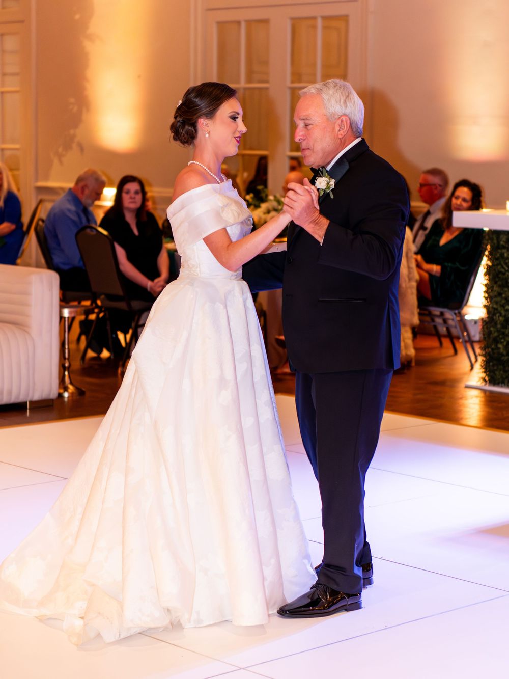A tender moment during a wedding dance on an elegant white dance floor.