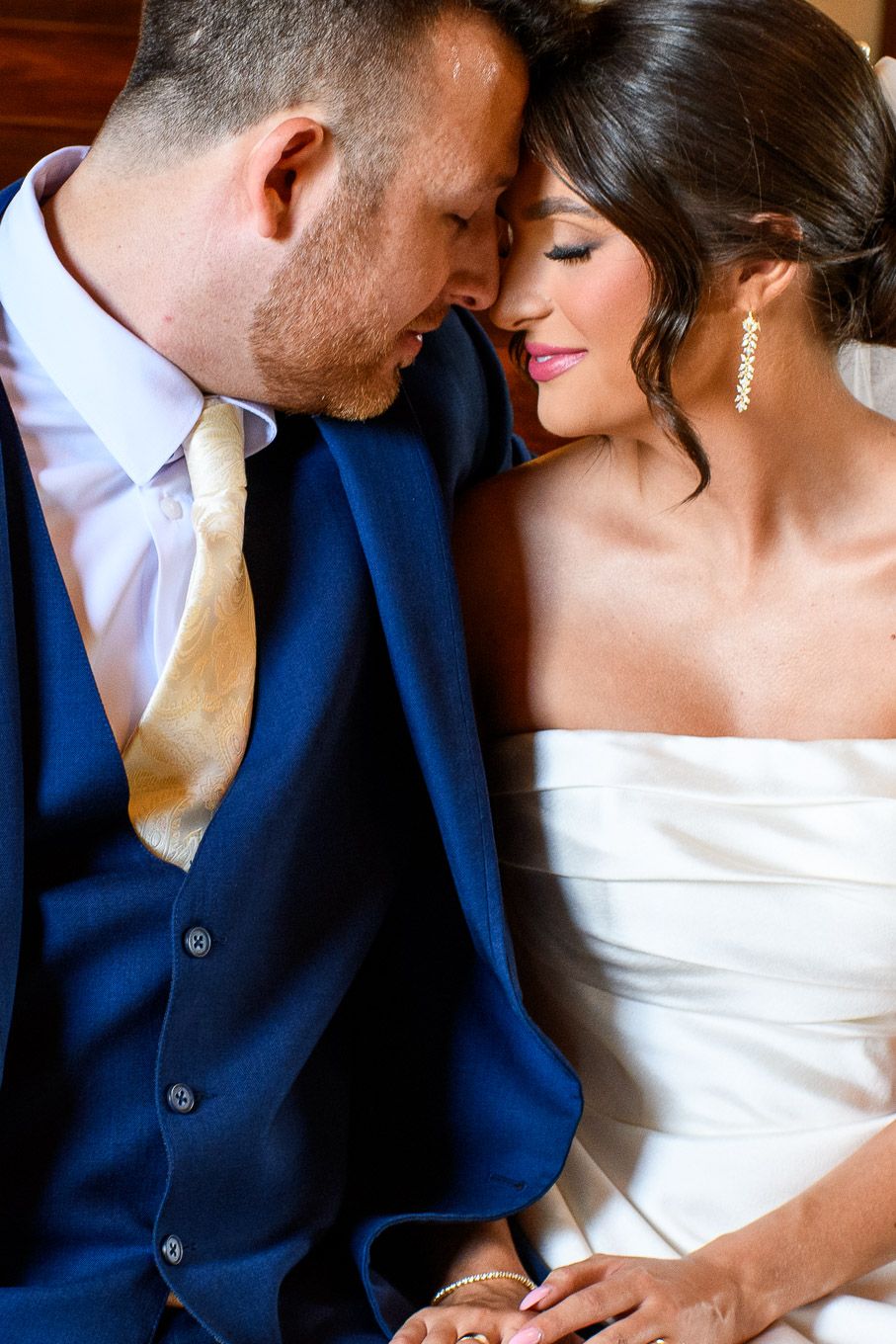 A romantic wedding moment showing close details of formal attire and elegant jewelry.