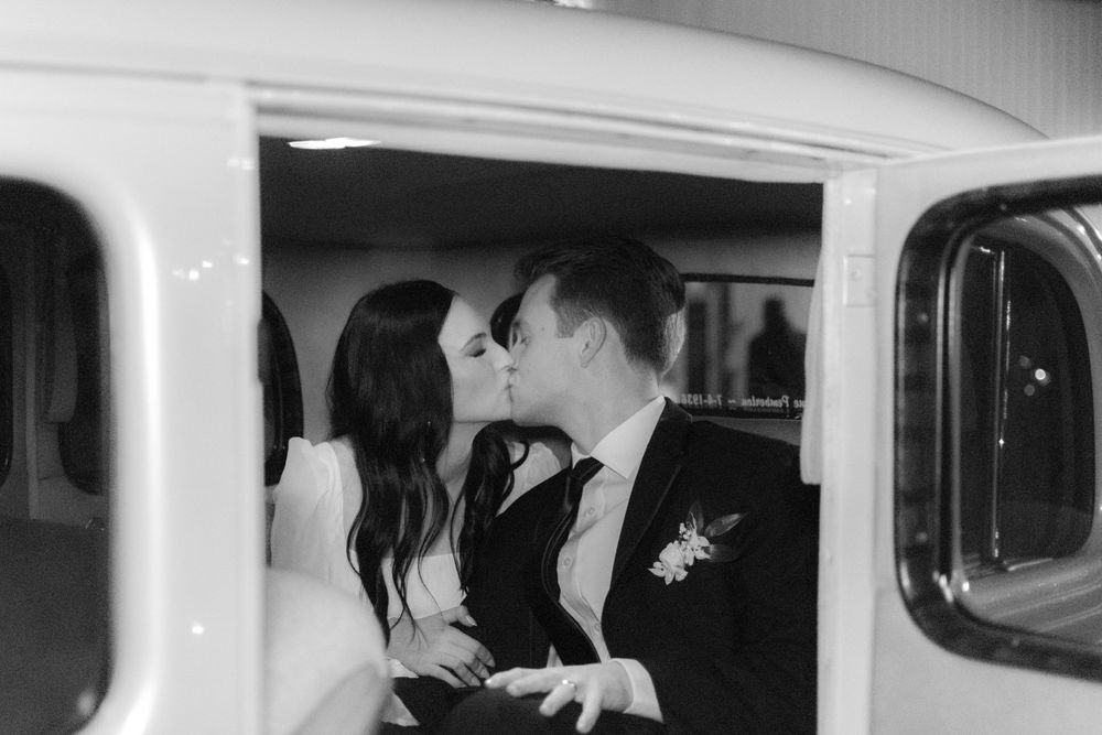 A black and white candid moment captured inside a wedding vehicle.