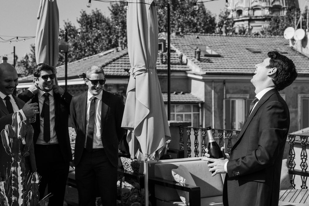 Outdoor wedding celebration with guests mingling under sunny skies captured in black and white.