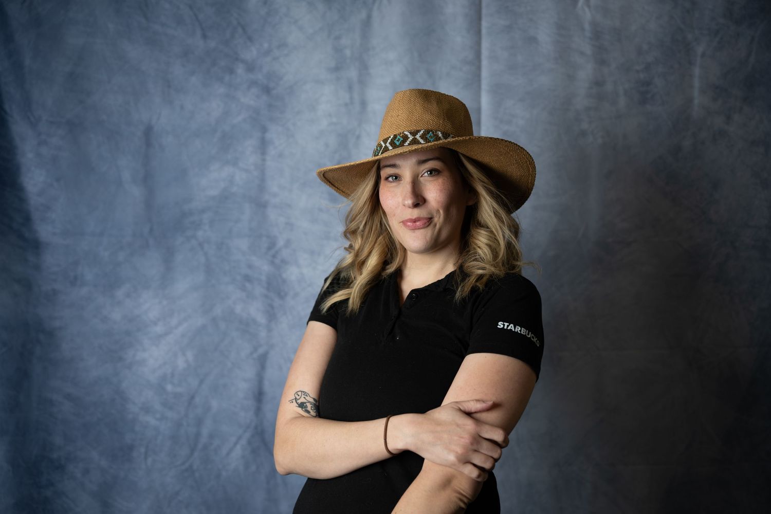 Portrait session showing person in black top and brown hat against dark backdrop.