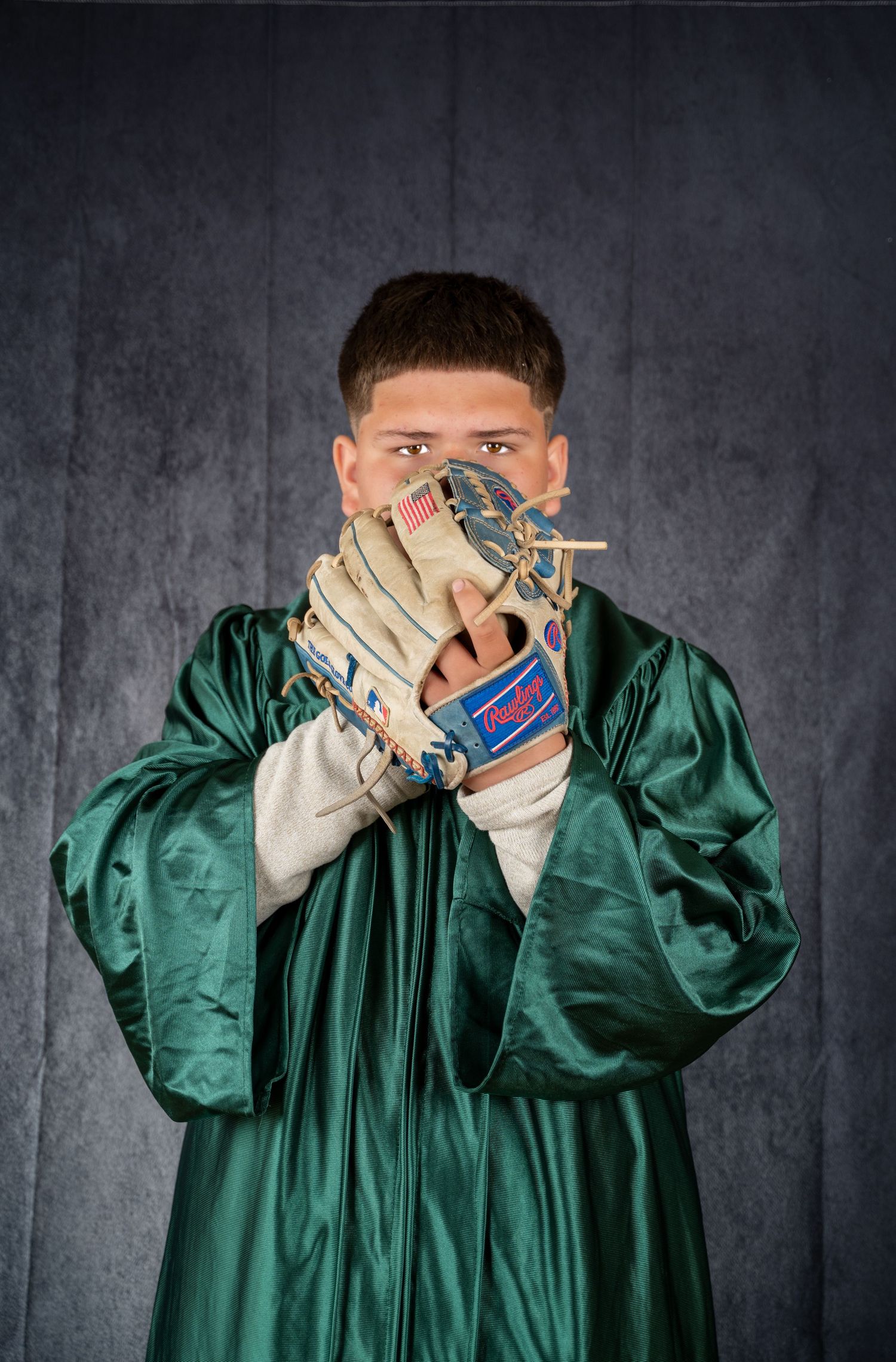 Person in green graduation gown making silly faces and gestures while posing for photos.