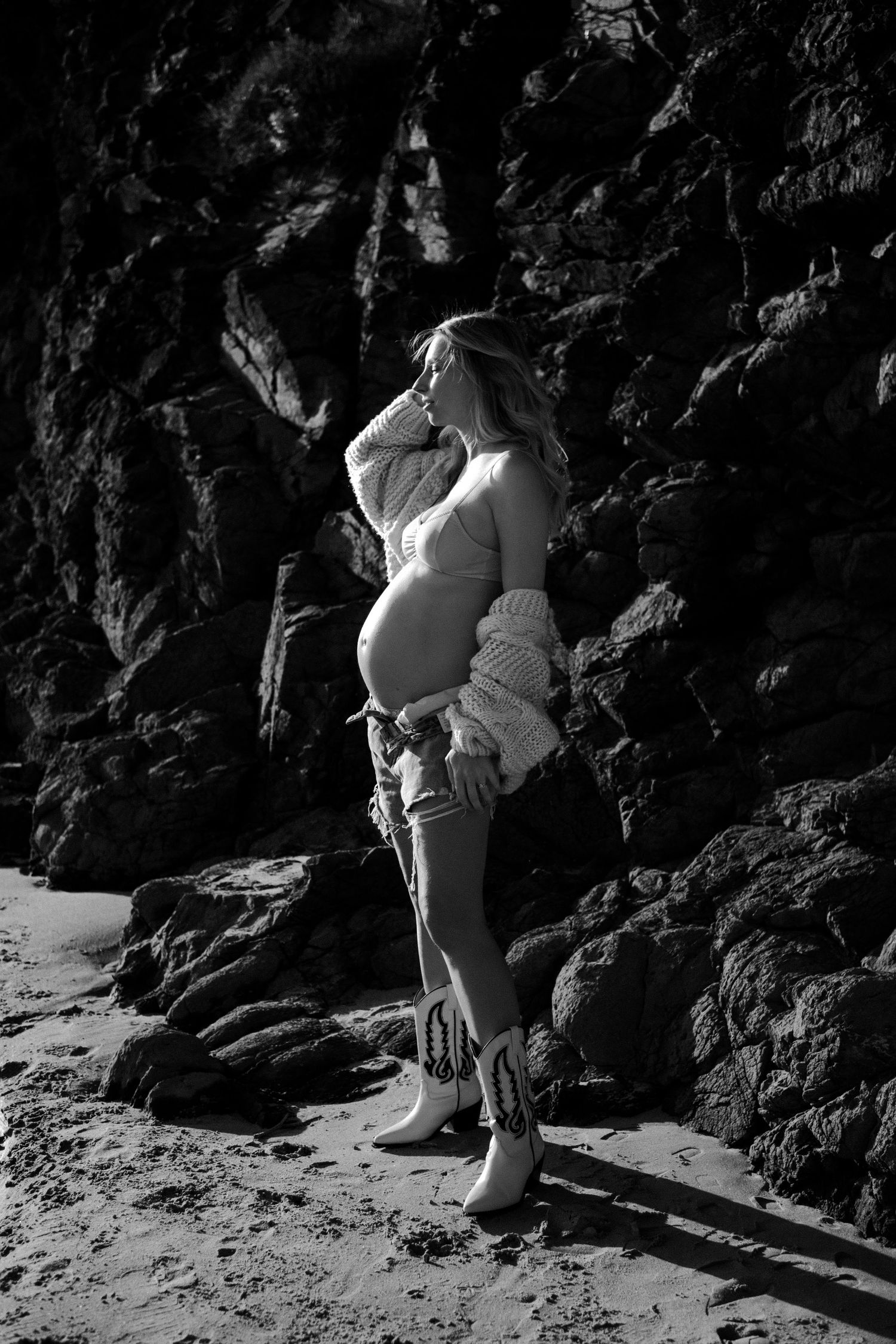 Black and white maternity photo against dramatic rocky backdrop.