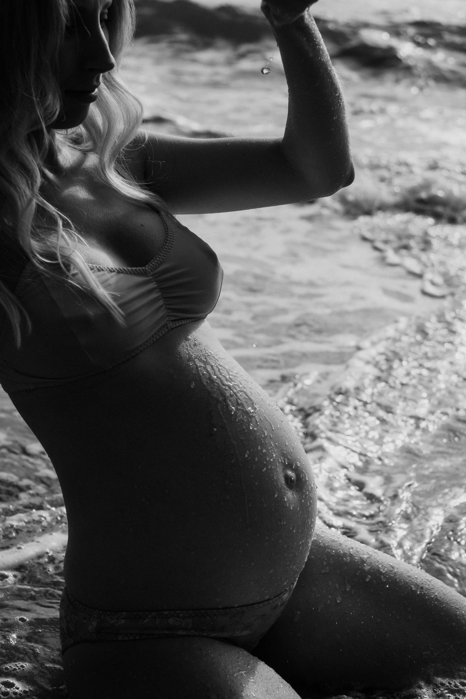 Silhouette of pregnant woman in beachwear by the ocean.