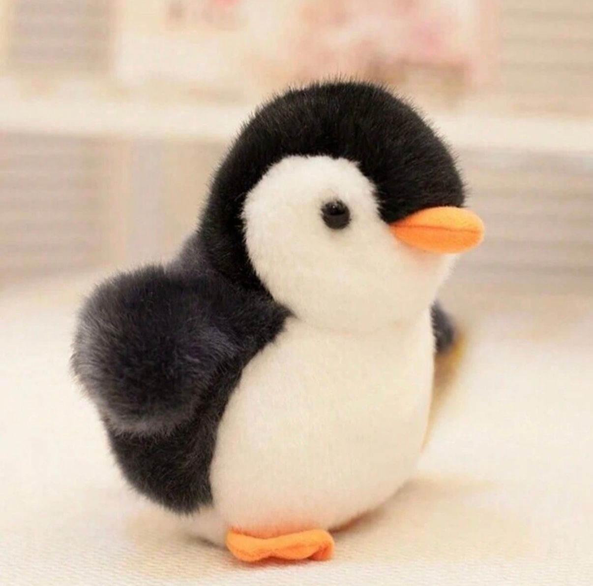 A plush penguin toy with orange beak shown from different angles on a light background.