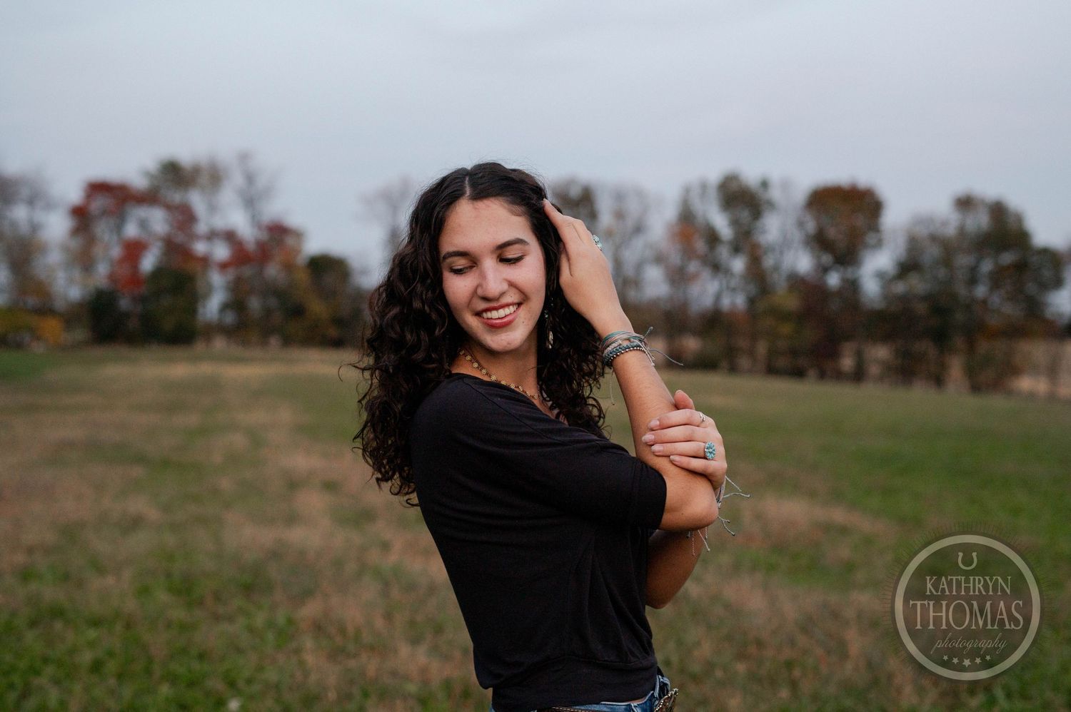 Candid moment captured of person with curly hair laughing in outdoor field.
