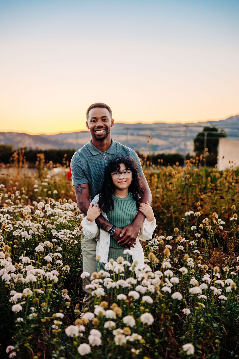 A sunset view in a flower field filled with white wildflowers and blooming plants during golden hour.