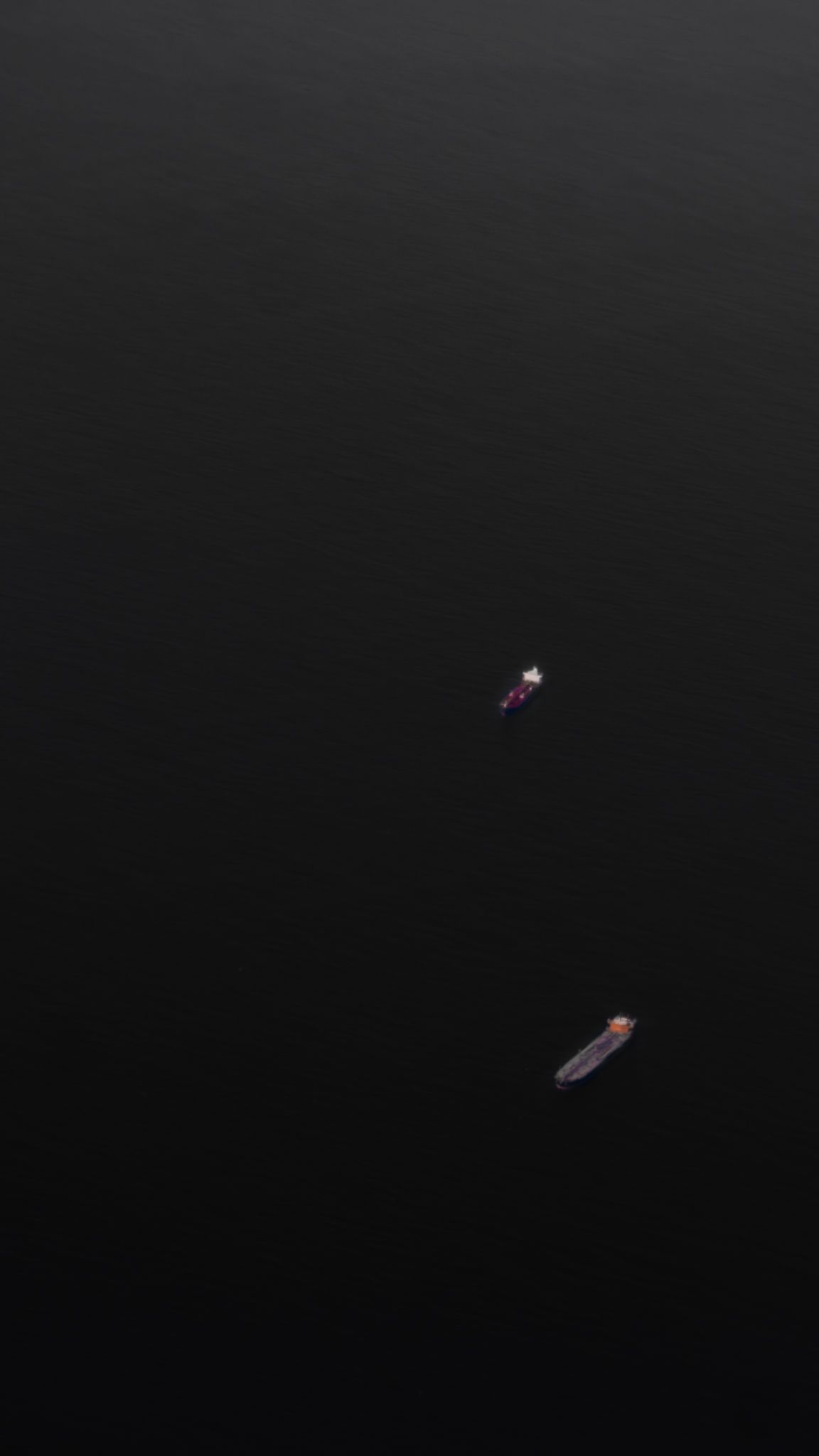 Two small glowing lights floating in a dark void create a minimalist composition.