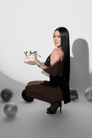 A figure in a dark bodysuit poses with silver balloons against a white backdrop in a minimalist photo series.