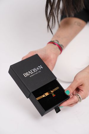 Hands opening and displaying a luxurious black Dr. Daxon branded gift box in a minimalist white studio setting.