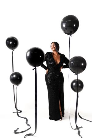 Glamorous evening shoot with black gown and decorative black balloons against white background.