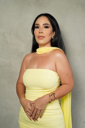 A person in a fitted yellow strapless dress poses against a gray textured wall in a series of photos.