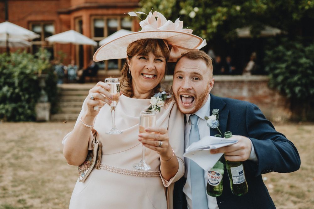 Wedding celebration with guests enjoying drinks and laughter at an outdoor garden reception.