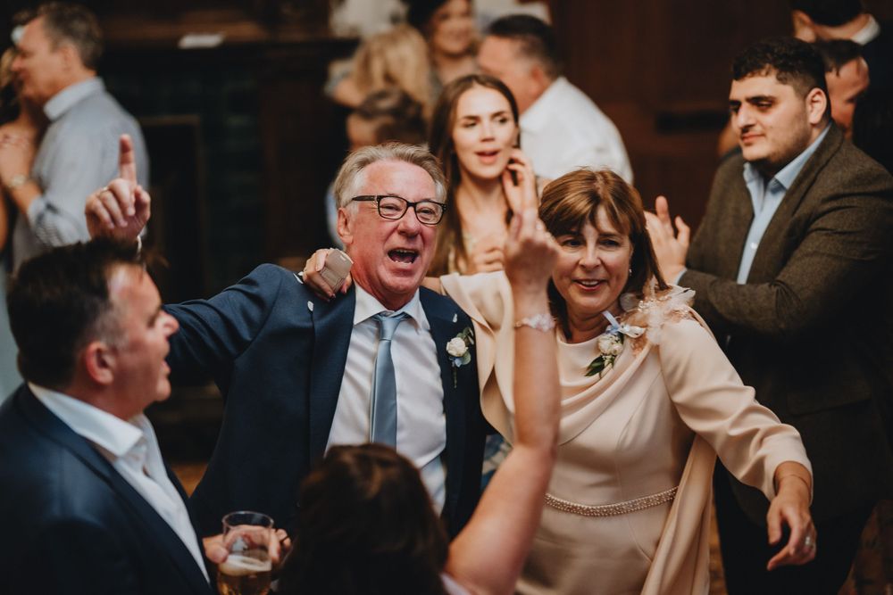 Wedding guests sharing an animated laugh together during a reception celebration.