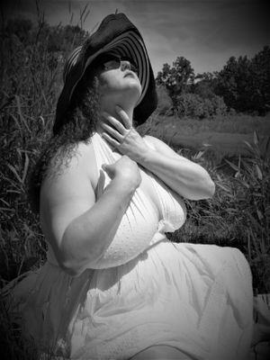 Atmospheric black and white image of someone in white clothing relaxing in a meadow.